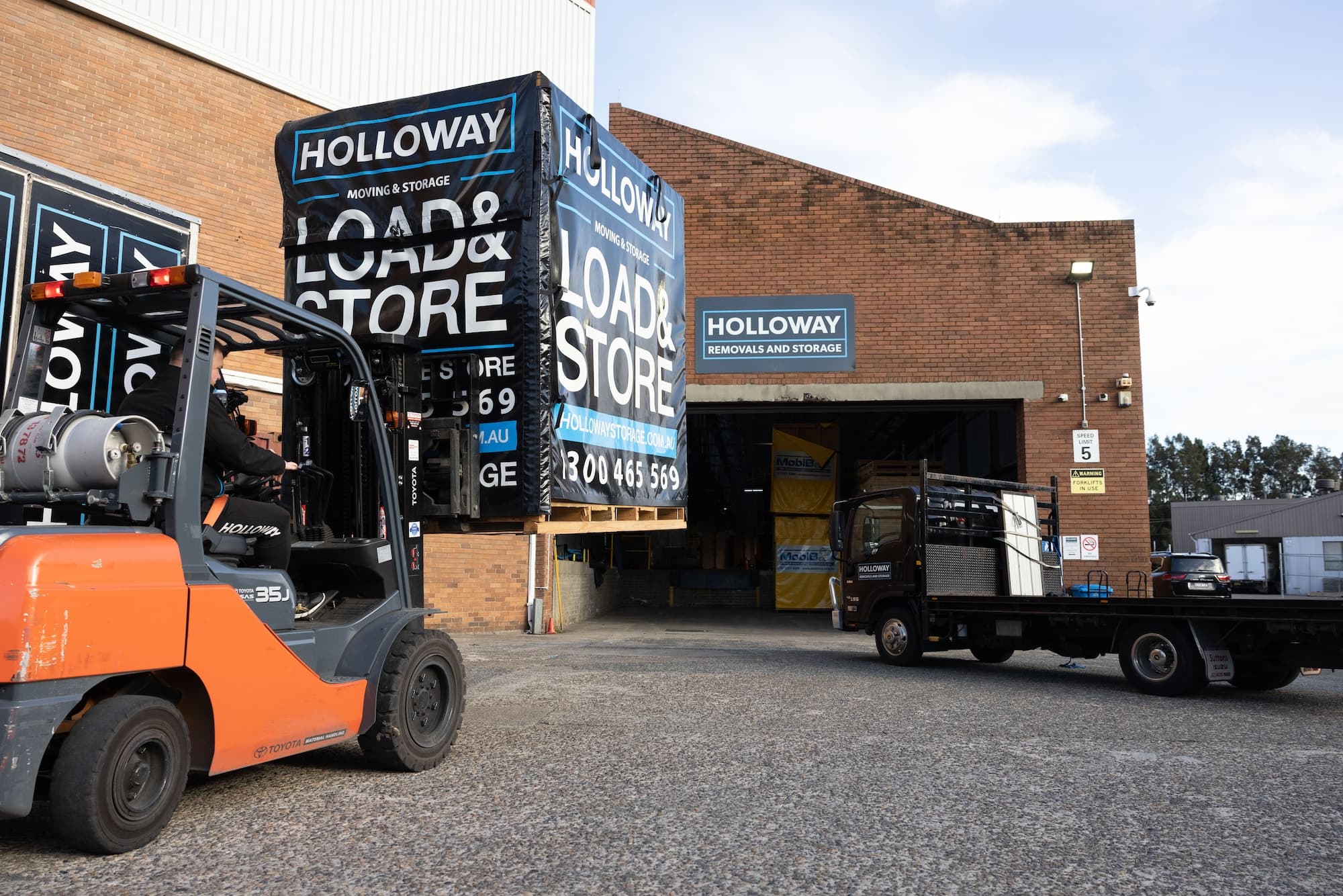 Forklift moving a storage module near a warehouse